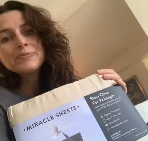 Dorothee M. from New York proudly holding Miracle Made Sheets, thrilled with the quality and feel
